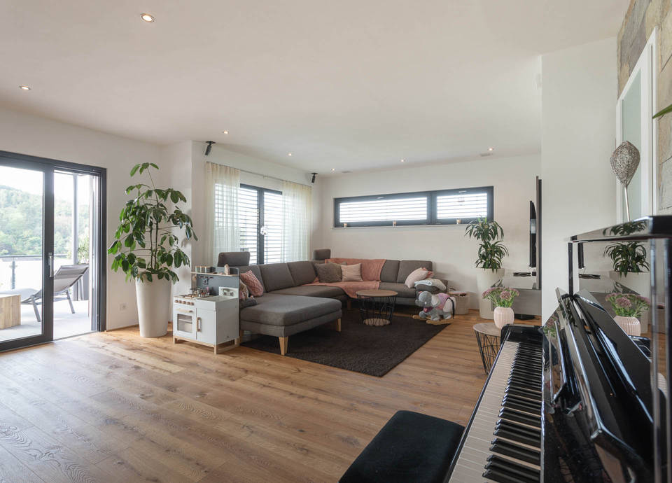 In dem individuellen Fertighaus bietet das große und helle Wohnzimmer mit Parkett viel Platz für die ganze Familie. Direkt an das Wohnzimmer schließt die großzügige Terrasse an.