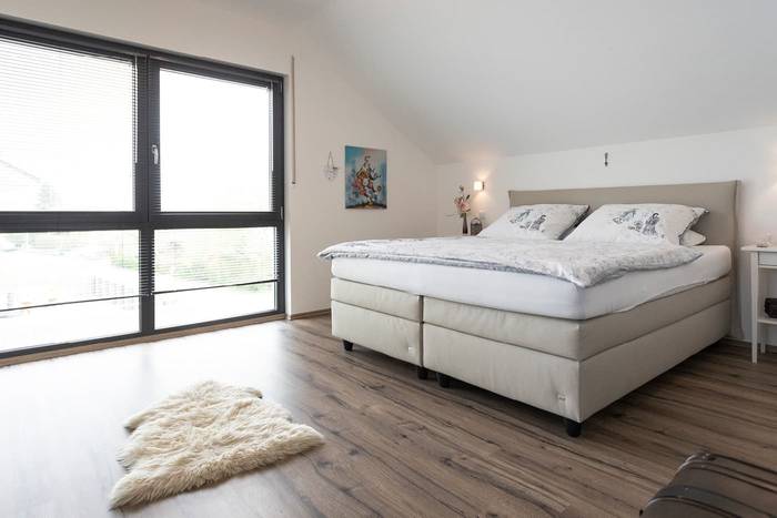 In dem großen Einfamilienhaus ist auch im Schlafzimmer viel Platz und die bodentiefen Fenster sorgen für Tageslicht und einer noch freundlicheren Raumatmosphäre.