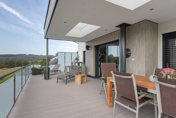 An das große und helle Wohnzimmer in dem modernen Fertighaus schließt direkt eine großzügige und wohnliche Terrasse an.