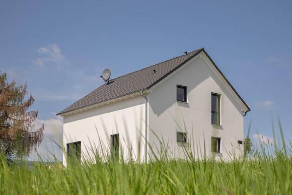 Das Architektenhaus von Büdenbender in Jesberg ist ein klassisch-moderner Wohntraum. Das Satteldachhaus hat eine weiß verputzte Fassade und dunkle Fensterrahmen. 