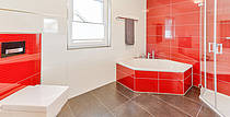 Musterhaus Florenzo, Badezimmer mit roten Fliesen, Badewanne und Dusche
