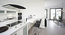 Musterhaus Bungalow Finess, offene moderne Hochglanzküche in weißer Optik mit Kochinsel